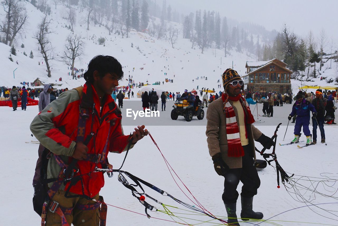 People on snow covered field against mountain