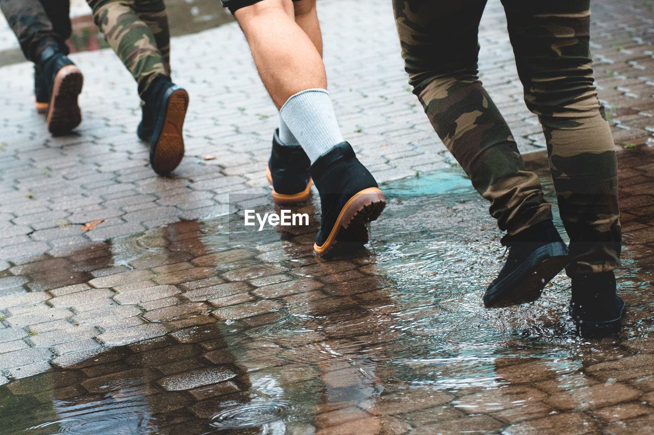 Low section of men walking on wet walkway