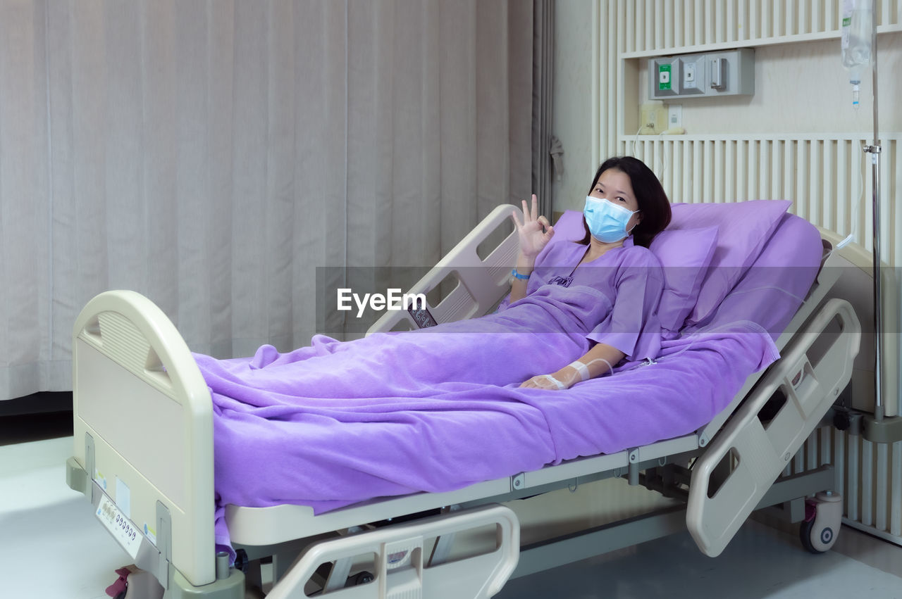 Female patient is smiling and showing ok gesture in hospital room. medical healthcare concept.