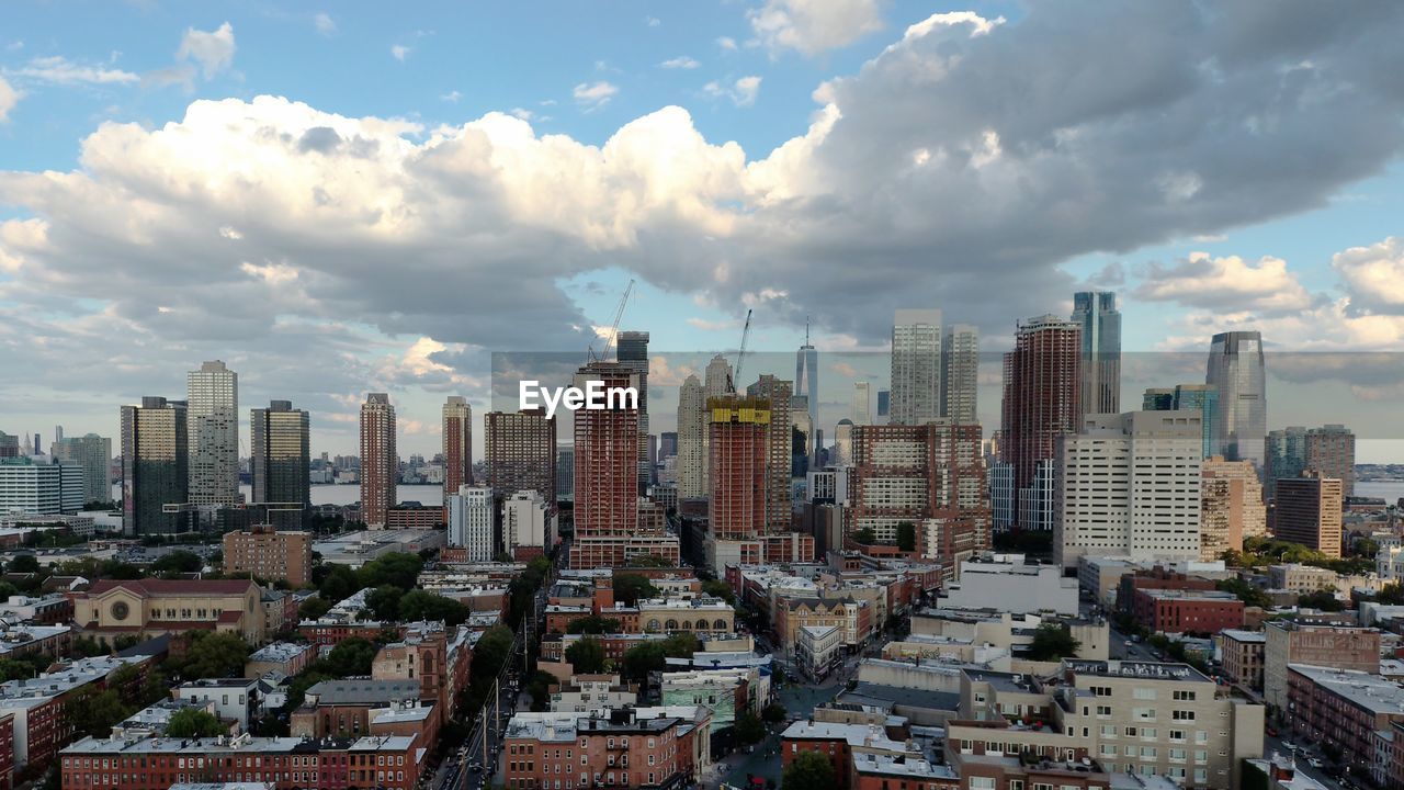 Aerial view of buildings in city against cloudy sky