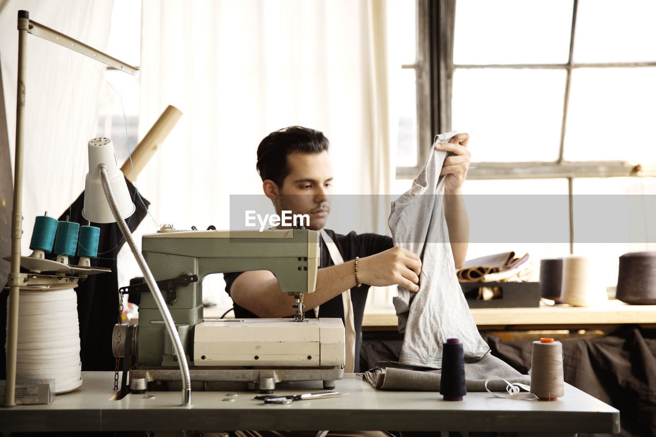 Fashion designer examining gray fabric while working at workshop