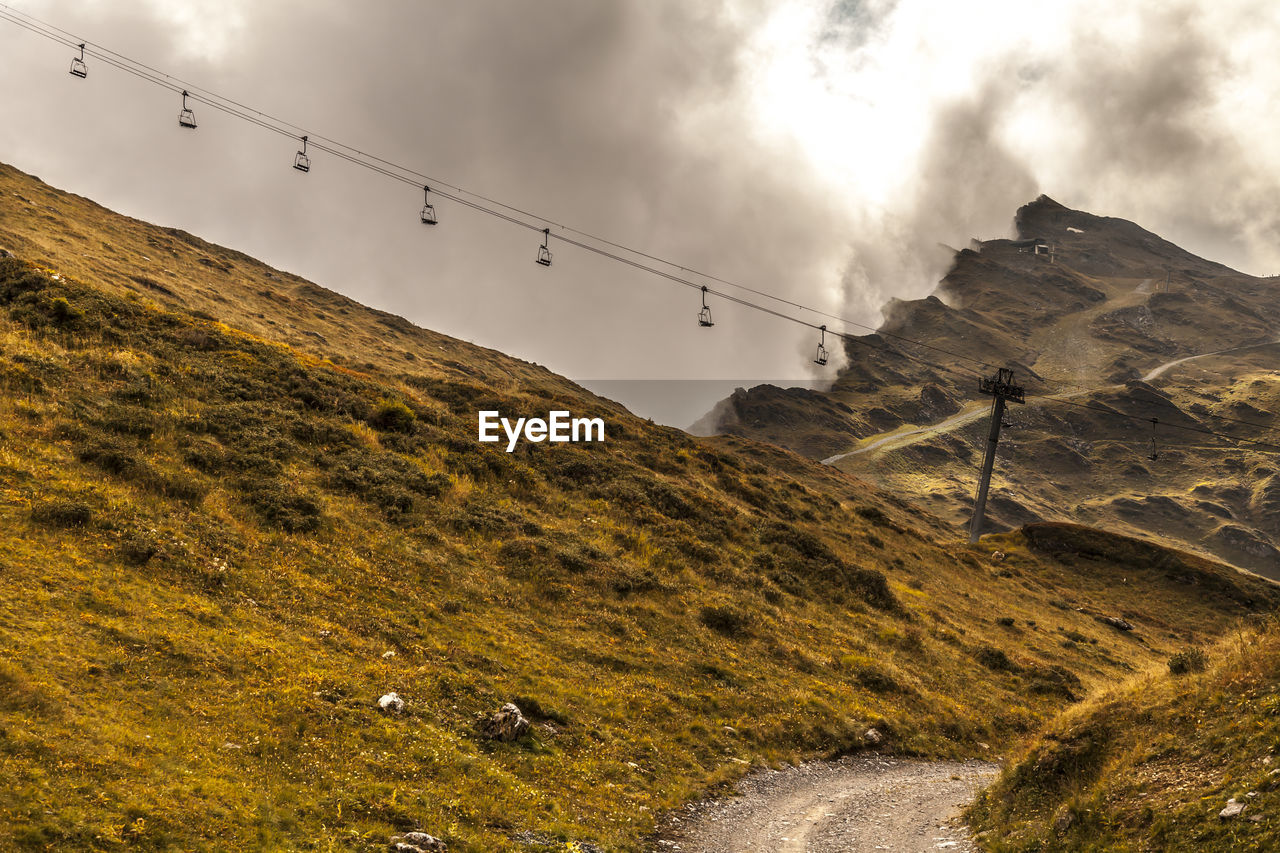 Side view of  chairlift againstcloudy  sky