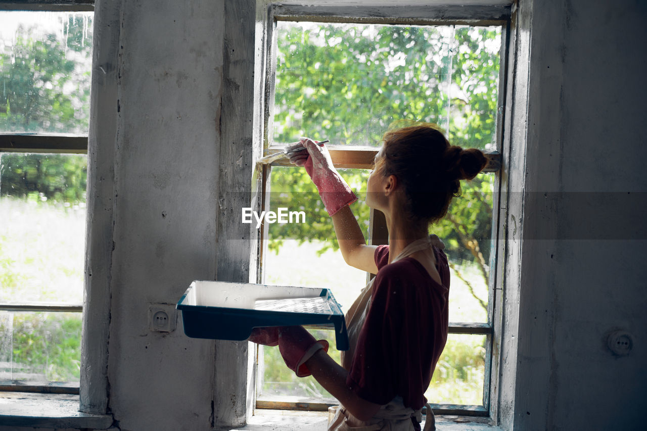 Side view of woman painting window