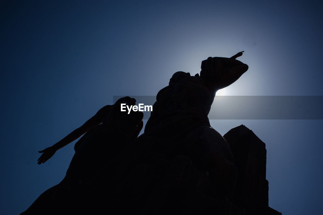 silhouette, darkness, sky, statue, low angle view, nature, sculpture, blue, clear sky, representation, backlighting, shadow, human representation, outdoors, person, architecture, cloud