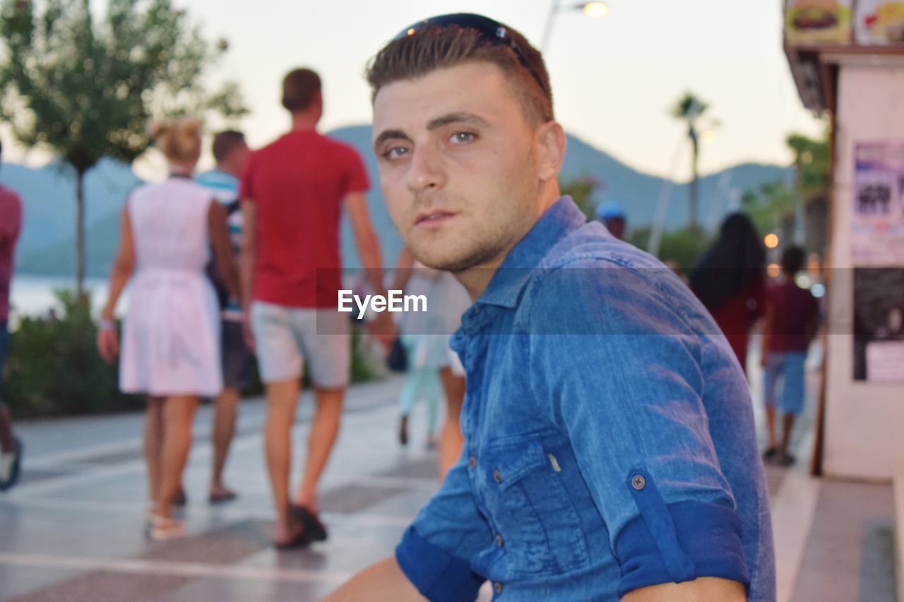 Portrait of man sitting on footpath during sunset