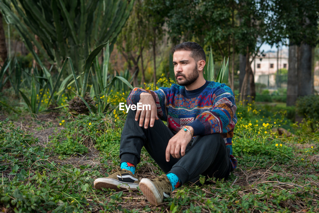 Caucasian model sitting on the ground in a public park