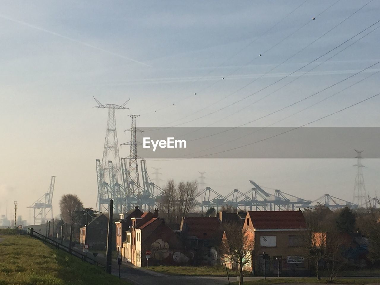 ELECTRICITY PYLON BY TREES AGAINST SKY