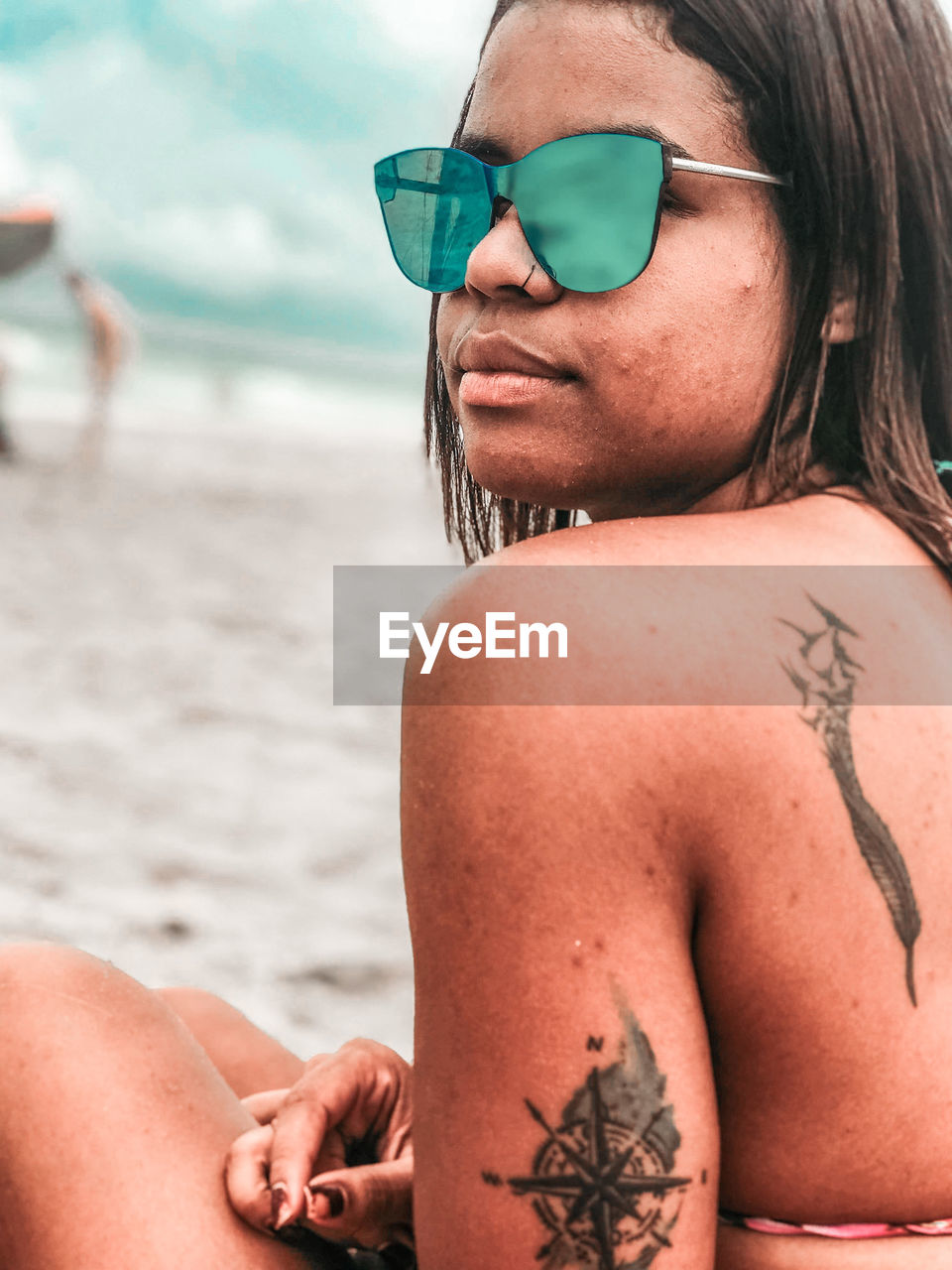 Midsection of young woman with sunglasses on beach