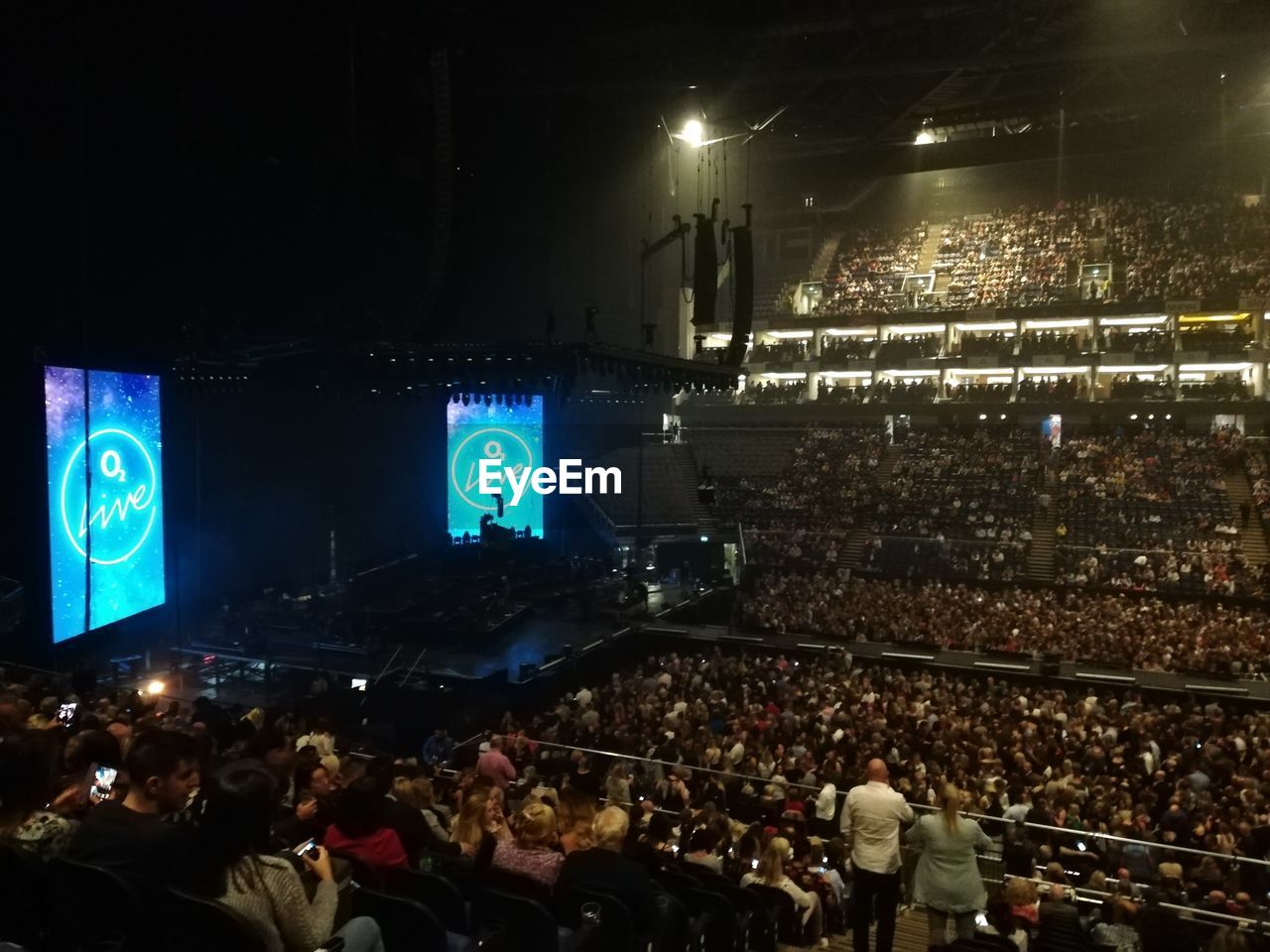 GROUP OF PEOPLE LOOKING AT ILLUMINATED STAGE