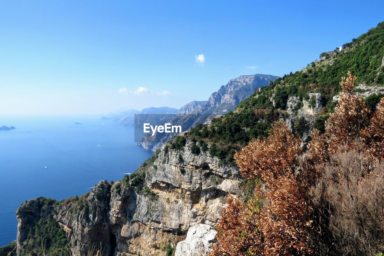 Scenic view of sea and mountains against clear blue sky