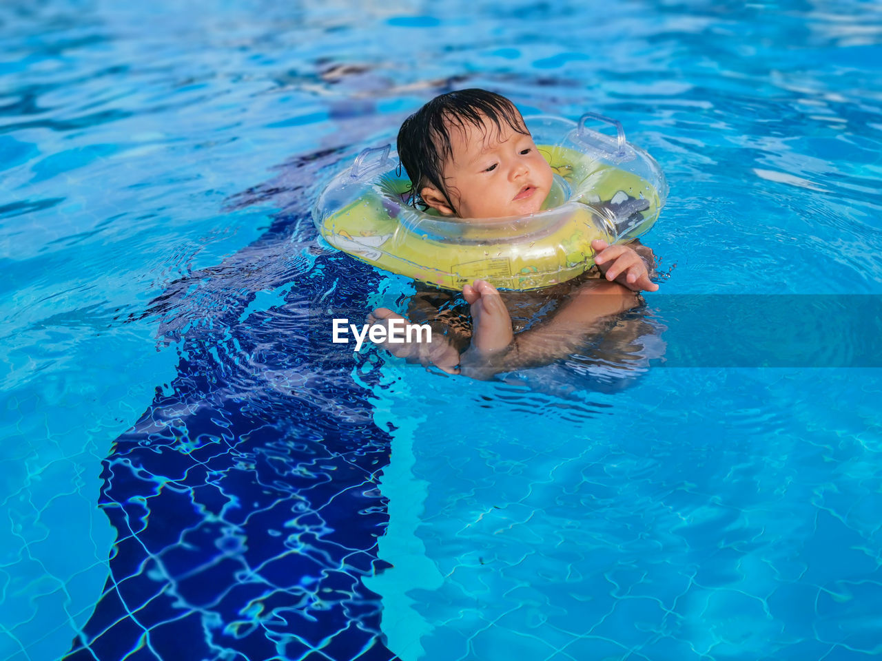 Baby learns to swim with extra swimming ring for babies