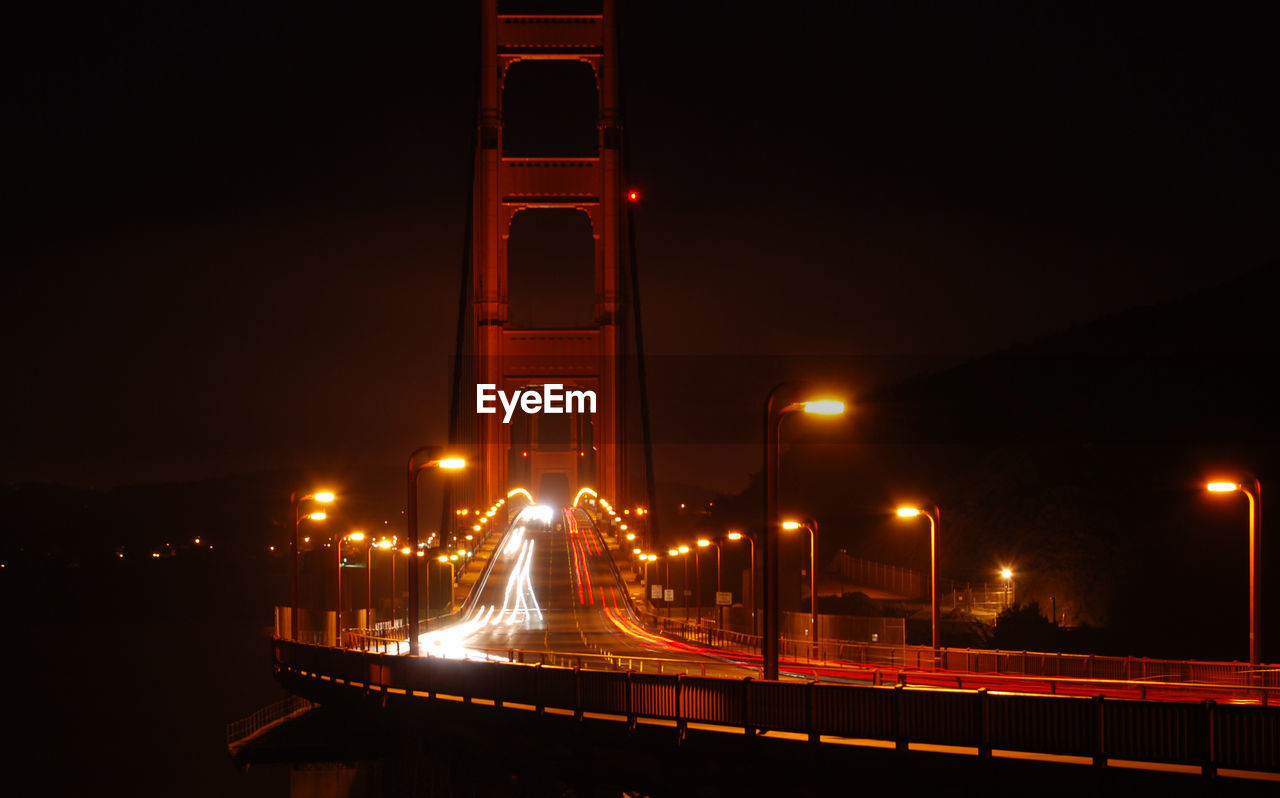 ILLUMINATED LIGHT TRAILS ON ROAD AGAINST SKY AT NIGHT