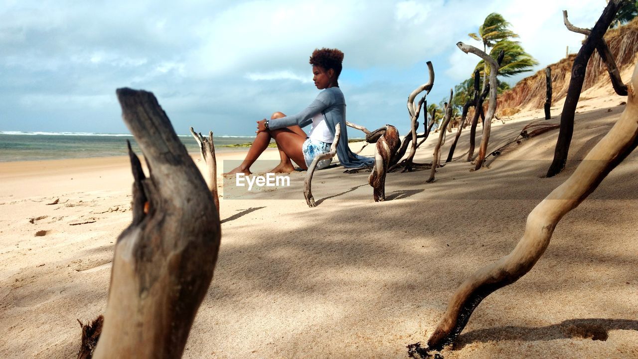 Young woman sitting on sand at beach