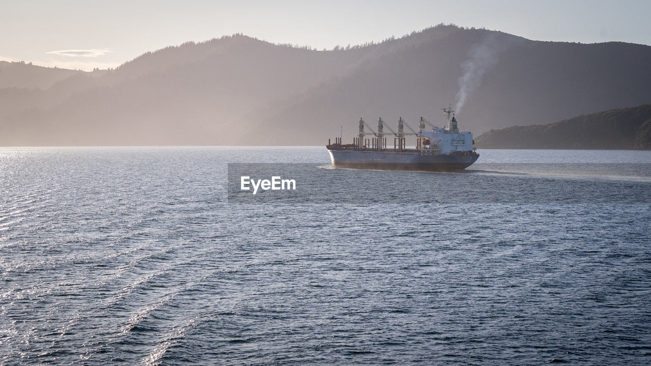 Large cargo ship leaving the port and sailing towards the sun, new zealand