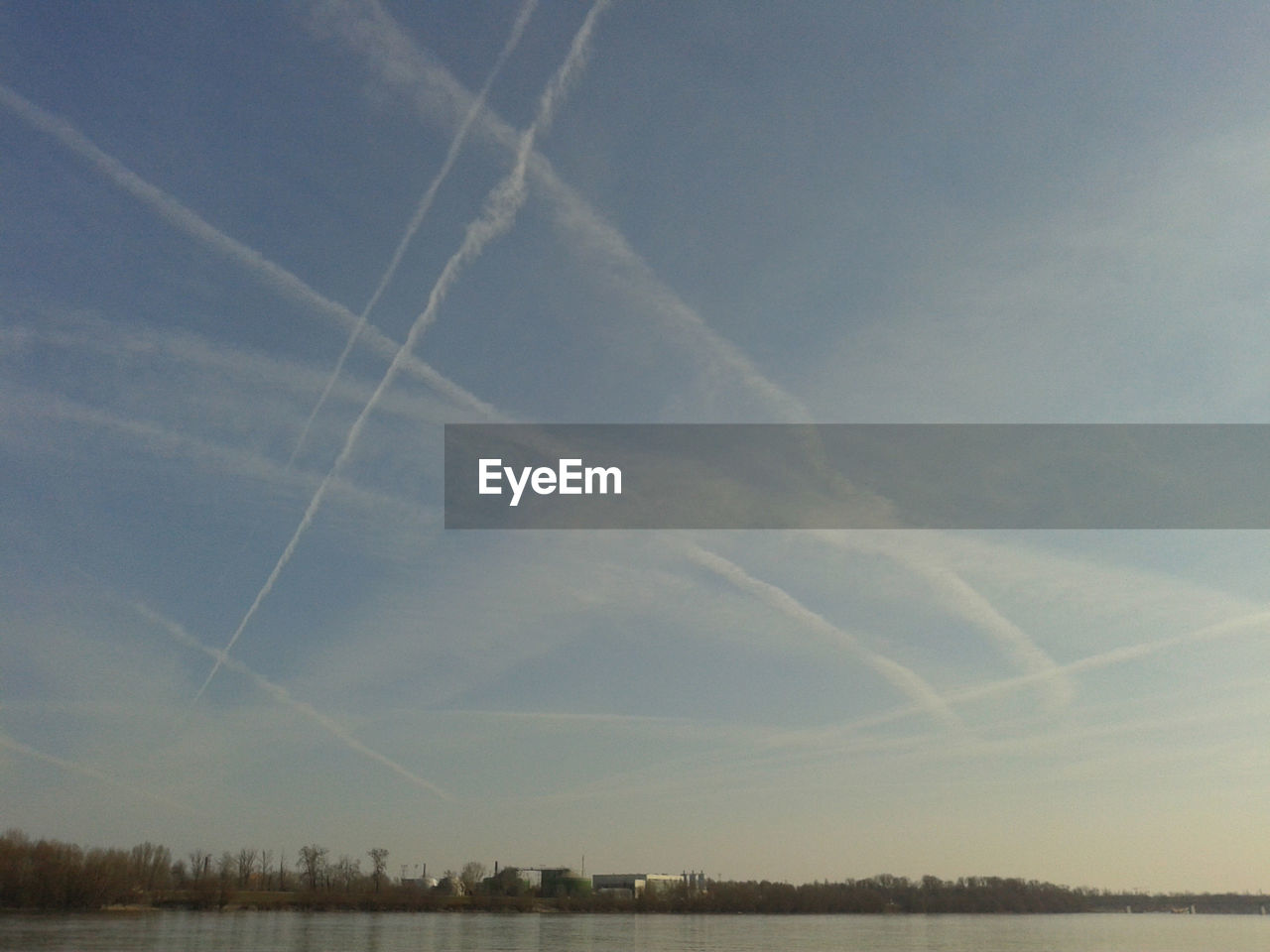 LOW ANGLE VIEW OF VAPOR TRAILS IN SKY OVER LANDSCAPE