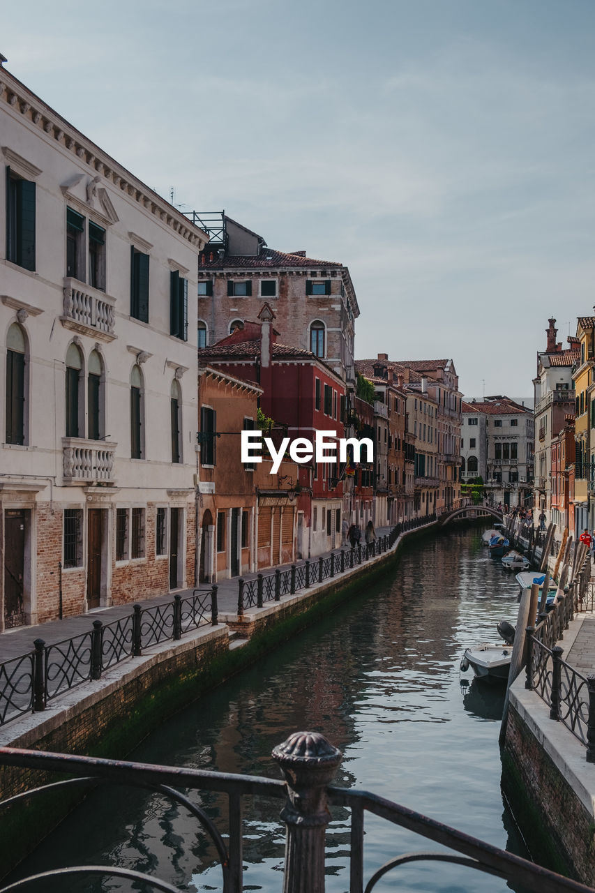 Canal amidst buildings in city against sky