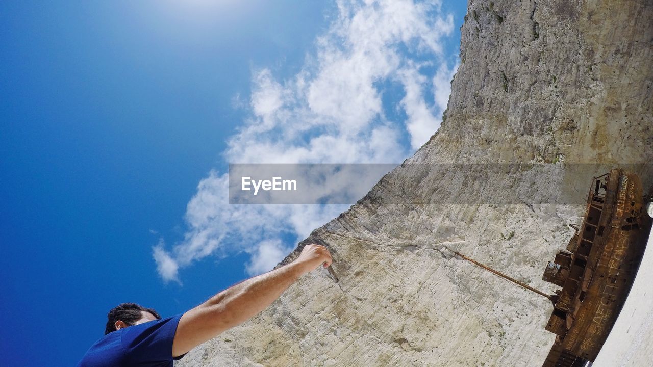 LOW SECTION OF MAN AGAINST BLUE SKY