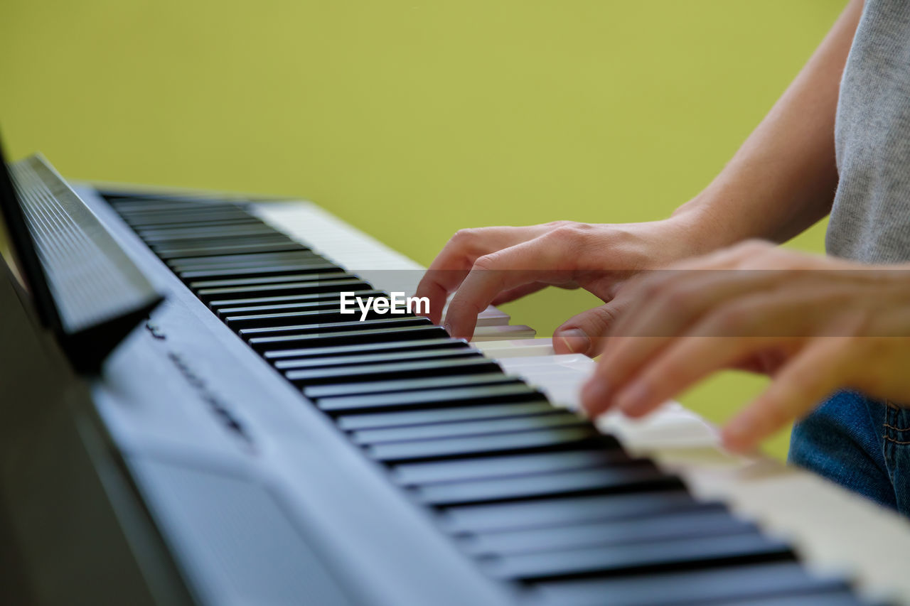 Hands of a girl playing the electronic piano. the girl plays the synthesizer.