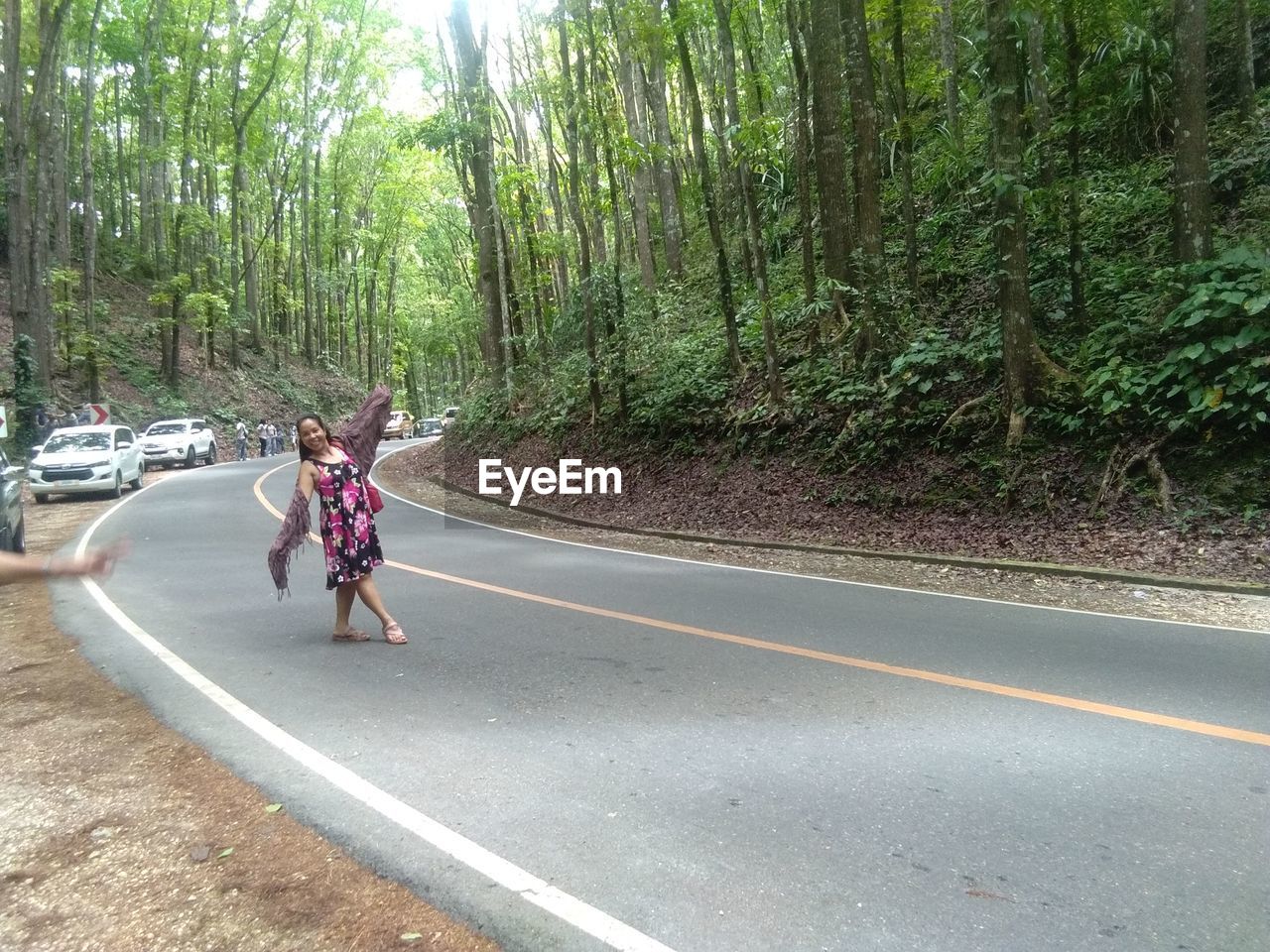REAR VIEW OF WOMAN ON ROAD AMIDST TREES IN FOREST