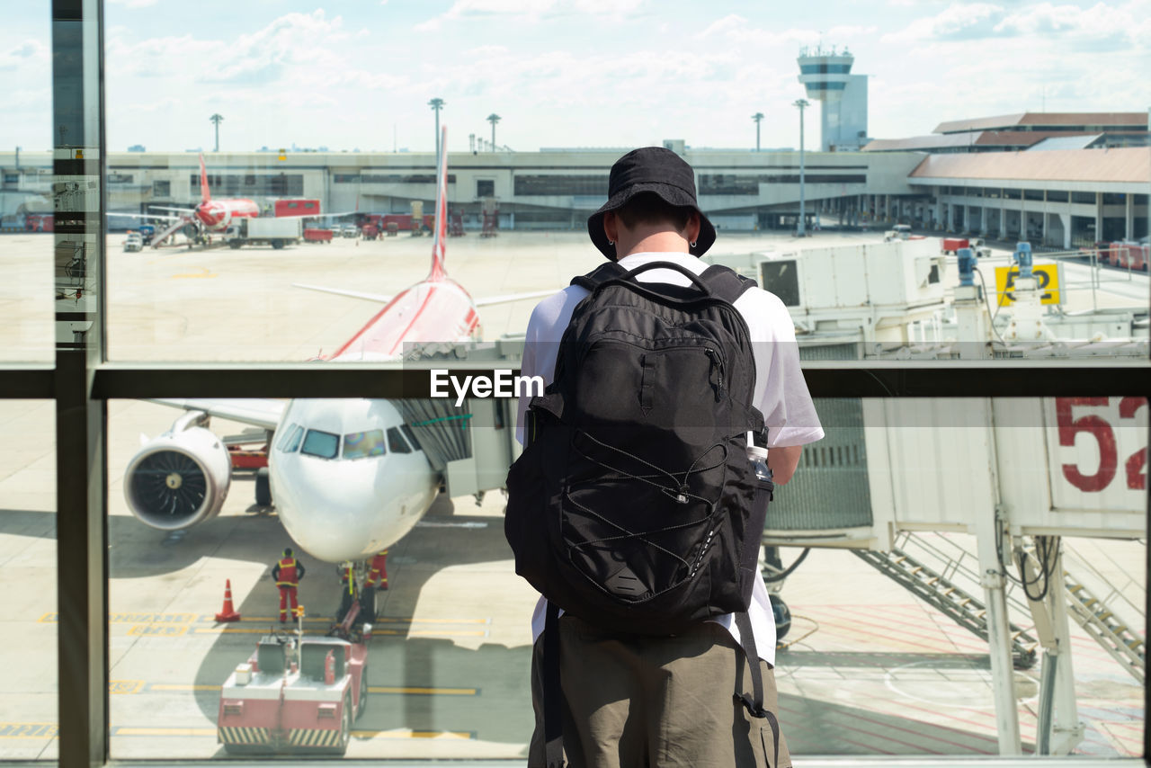 airport, one person, transportation, rear view, air vehicle, mode of transportation, airplane, standing, architecture, vehicle, day, men, adult, travel, occupation, aviation, airport runway, infrastructure, uniform, person, clothing, outdoors, air force, security