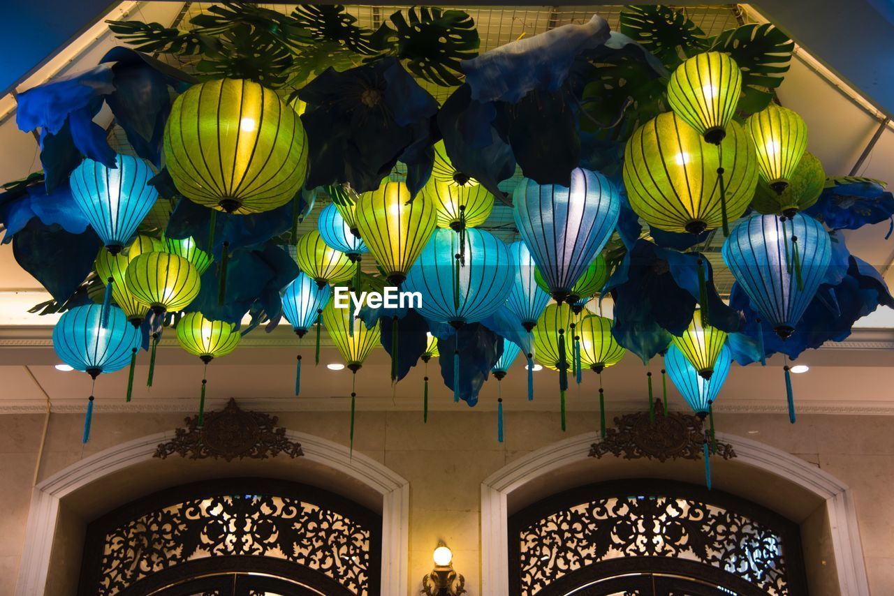 LOW ANGLE VIEW OF ILLUMINATED CHANDELIER HANGING FROM CEILING