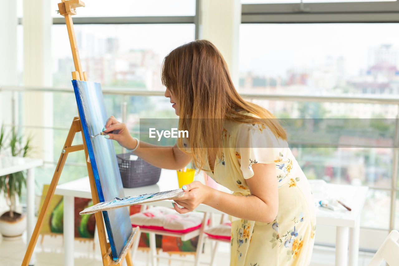 Woman painting on canvas at home