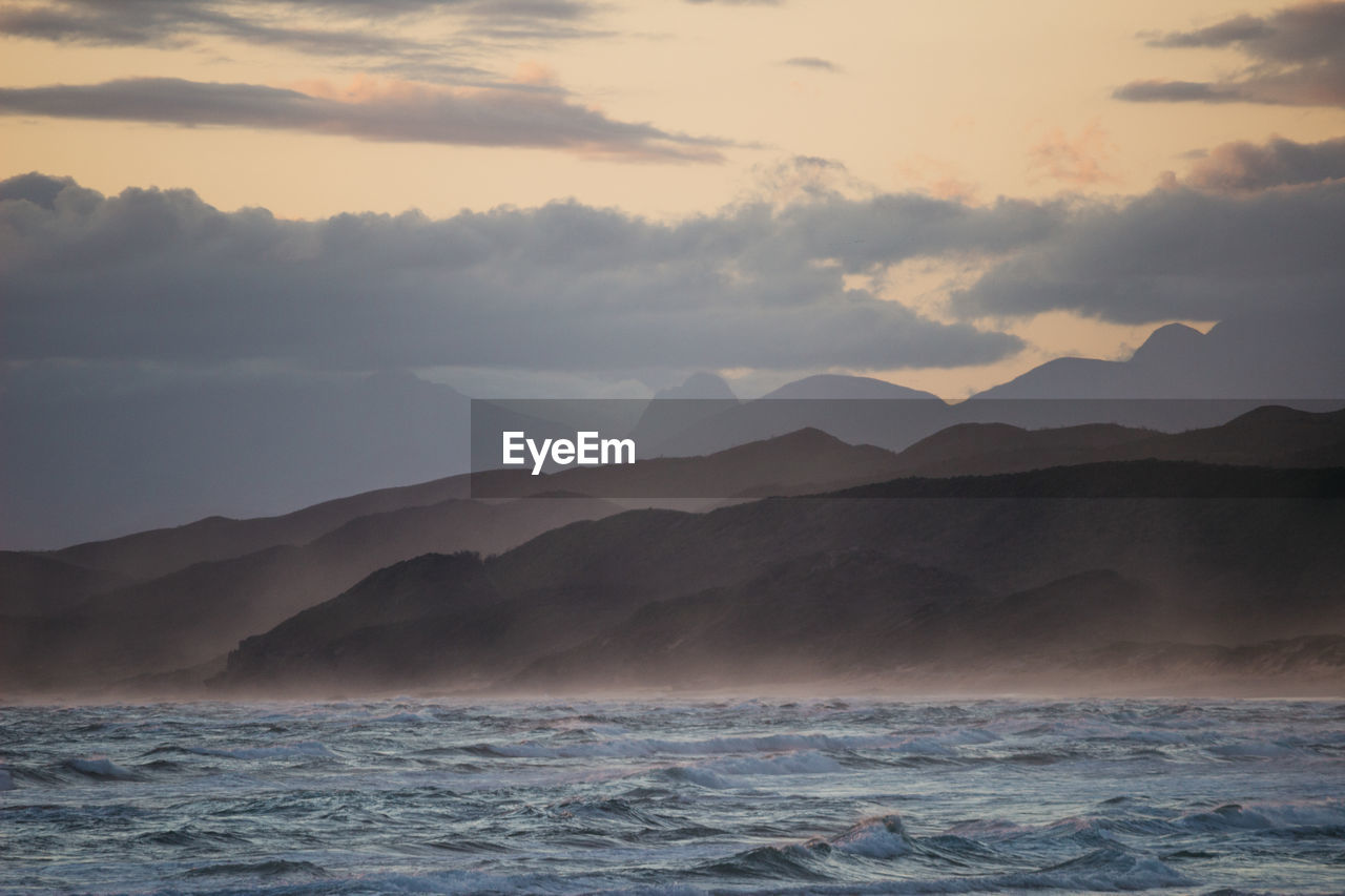 SCENIC VIEW OF SEA BY MOUNTAINS AGAINST SKY