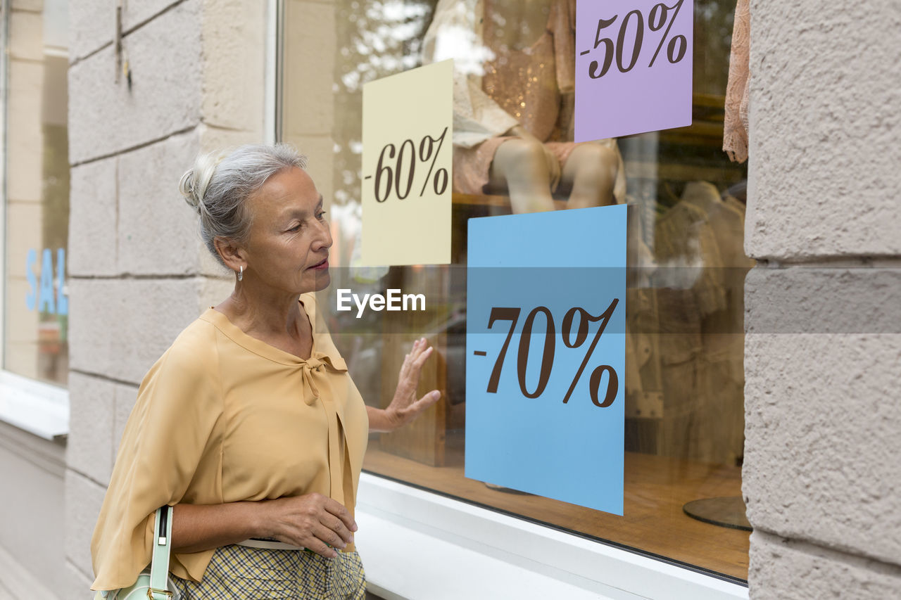 Senior woman looking in shop window of a boutique