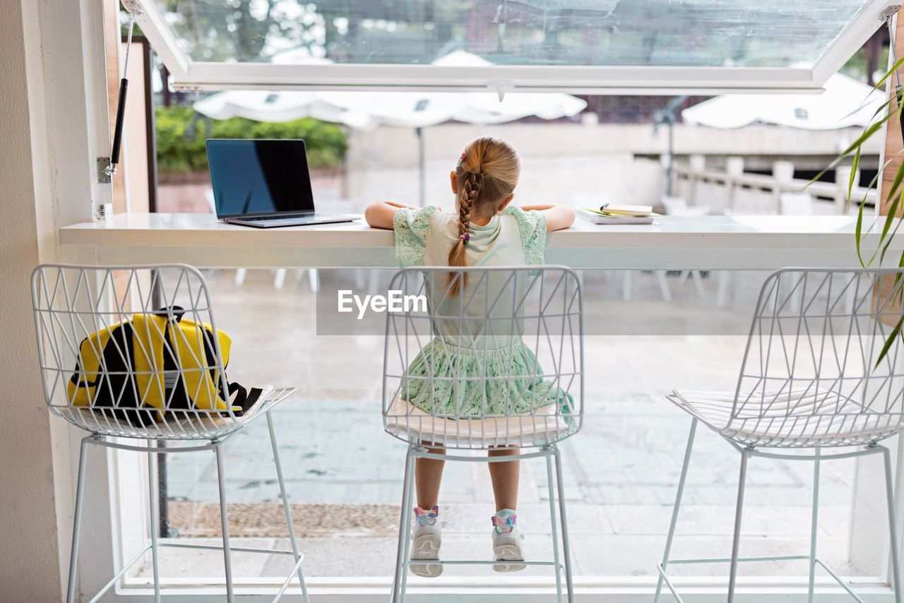 Rear view of girl doing homework at home