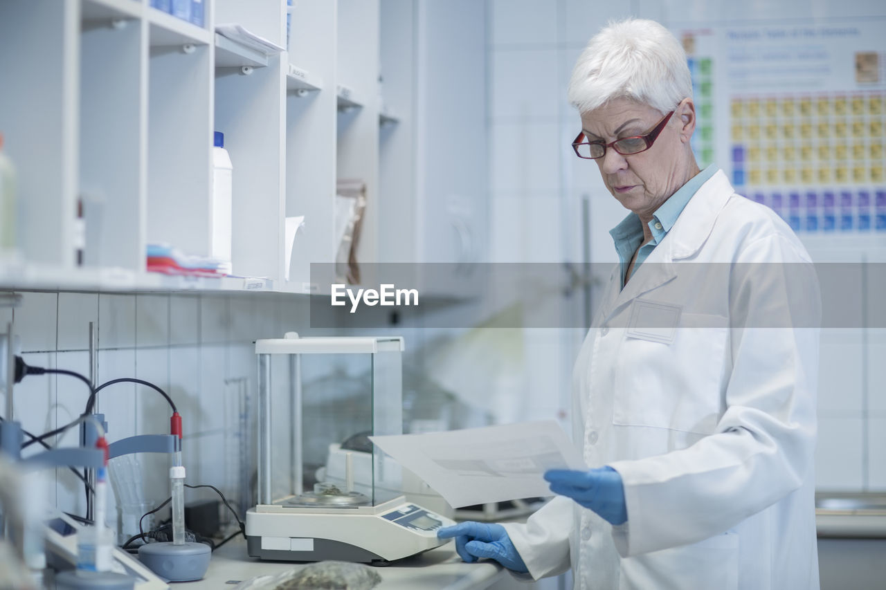 Senior woman in lab looking at paper