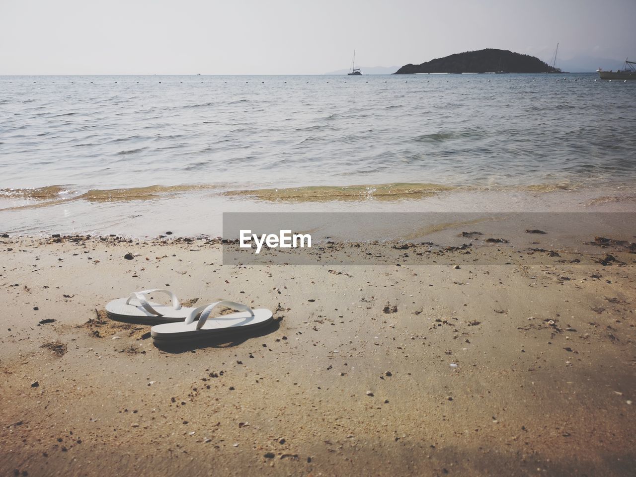 HIGH ANGLE VIEW OF SHOES ON SAND AT BEACH