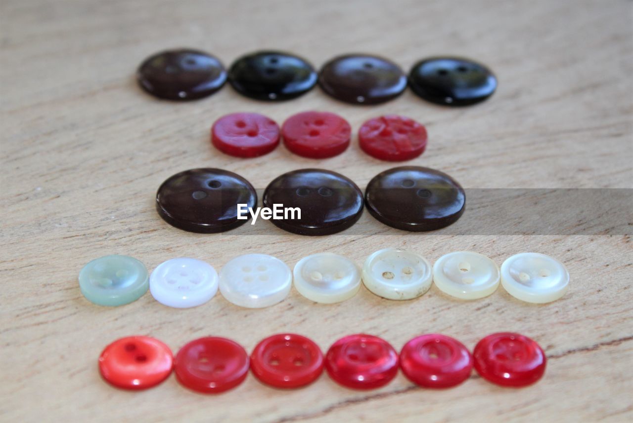 Colorful buttons arranged on wooden table