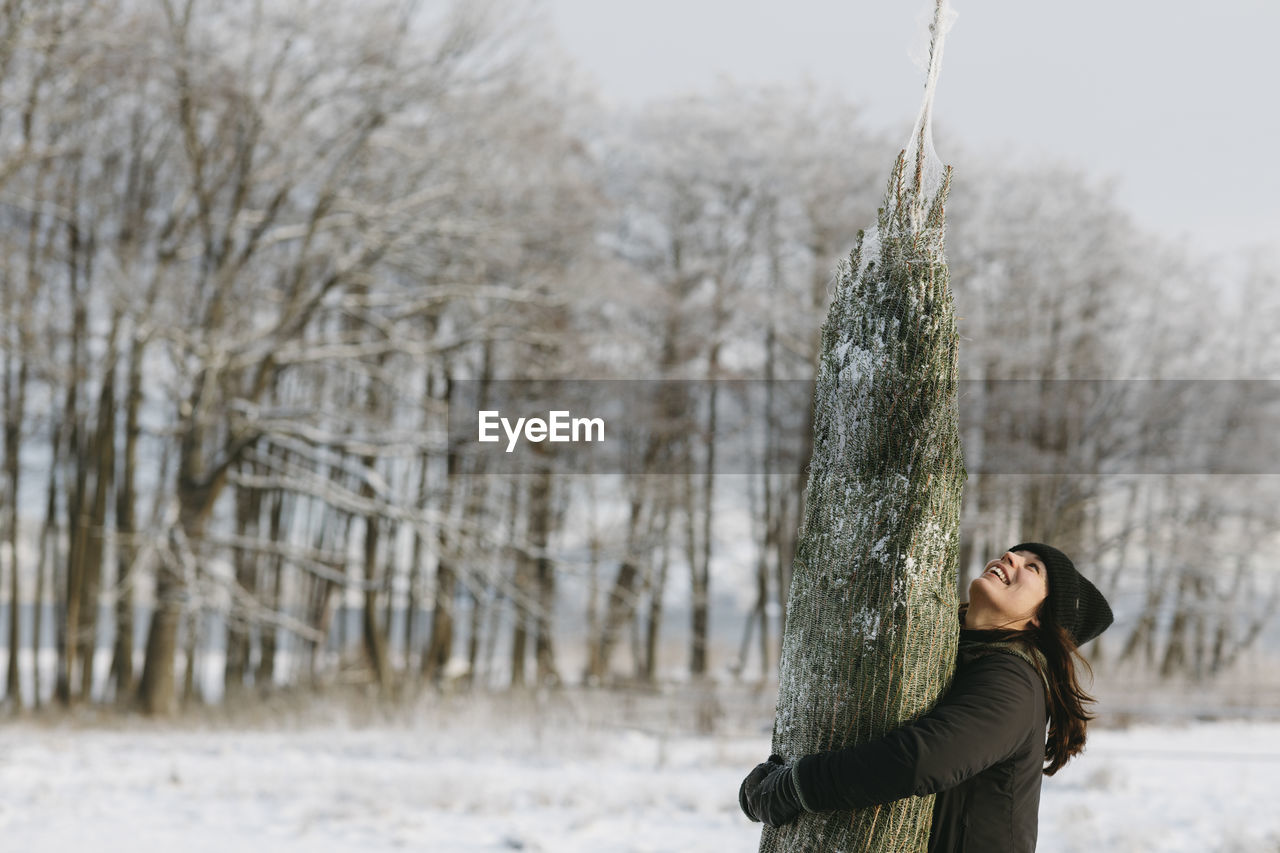 Woman carrying christmas tree at winter