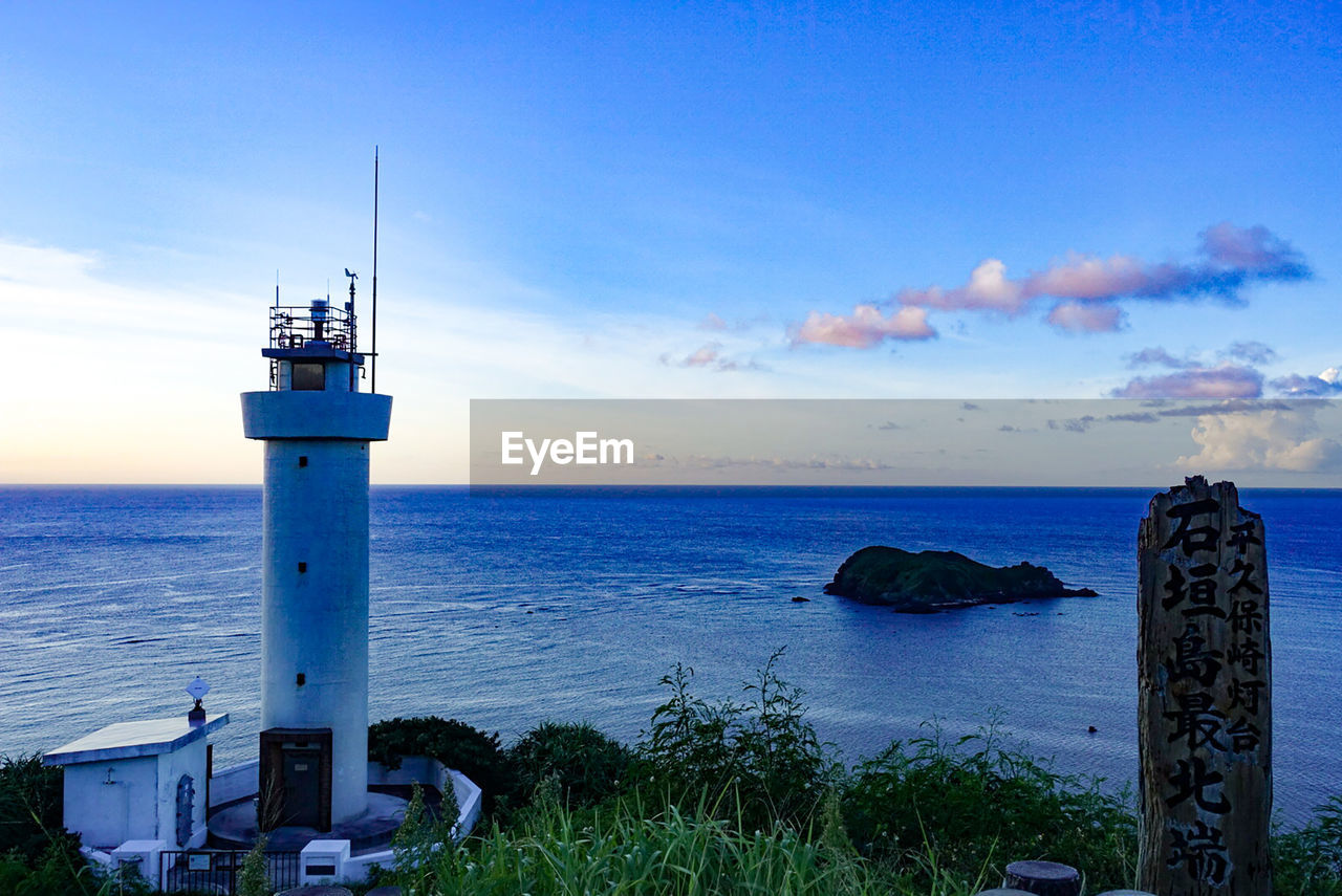 Lighthouse by sea against sky