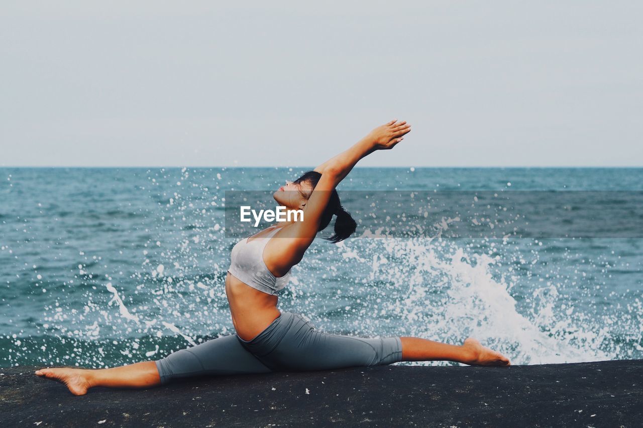 Woman practicing yoga on the beach 