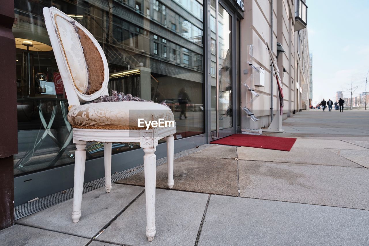 EMPTY CHAIRS ON SIDEWALK BY BUILDING