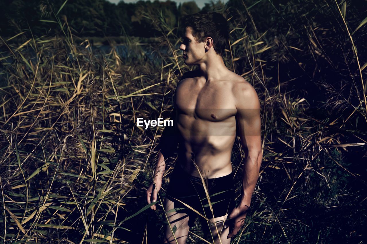 Handsome young man standing on grassy field