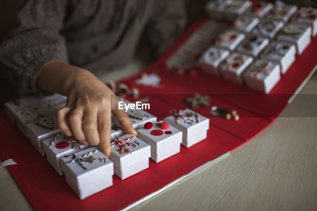 Midsection of girl sitting by christmas gift at home