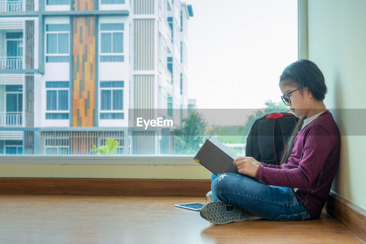 Girl reading book while sitting at home