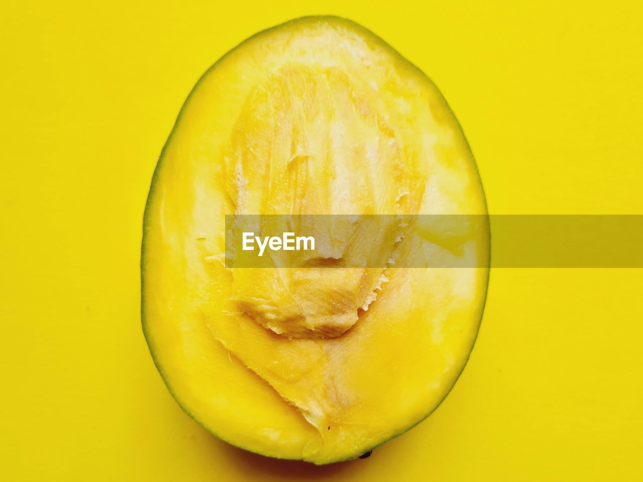 Mango cut in half on yellow background