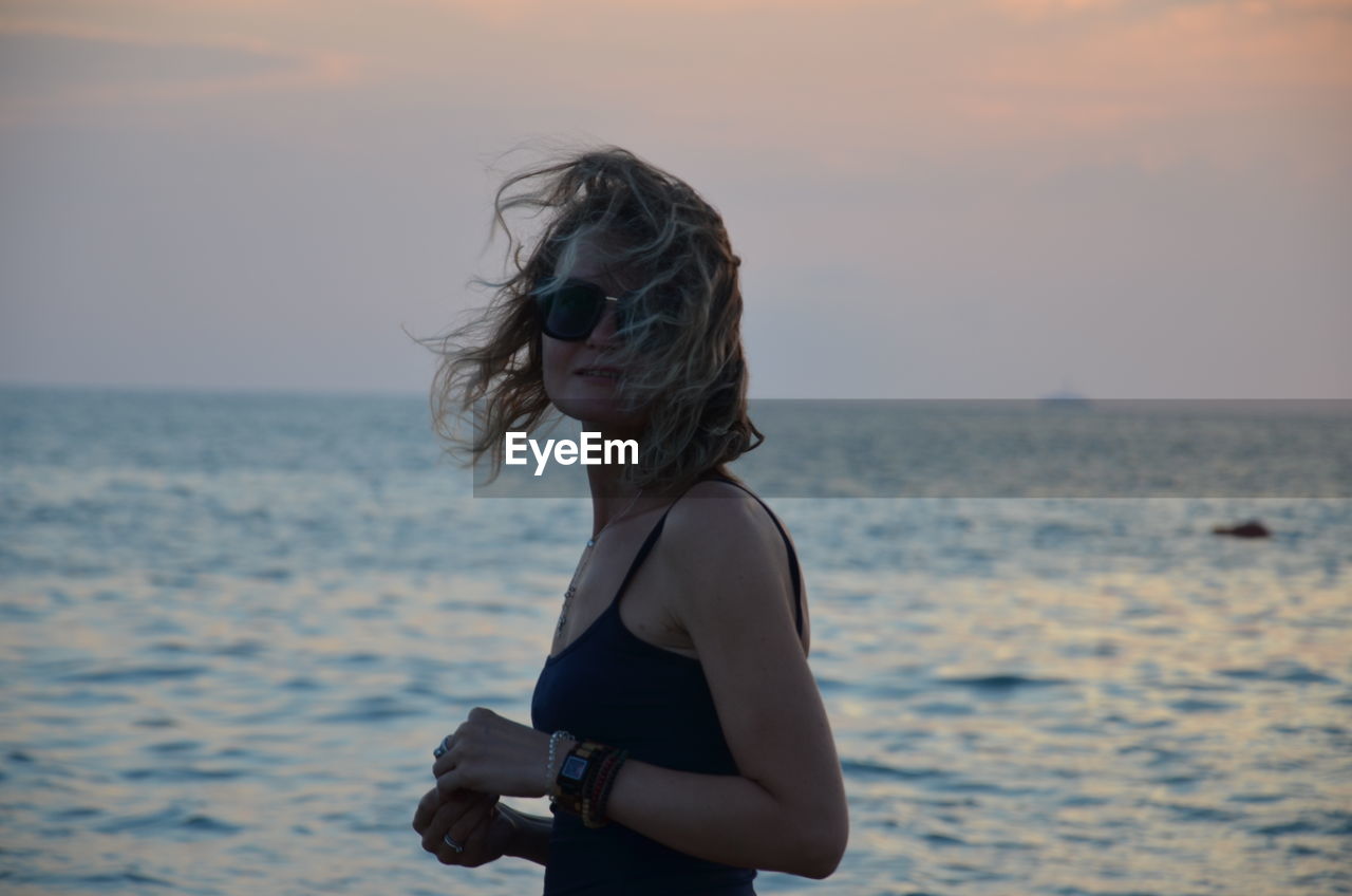 Full length of woman on beach against sky during sunset