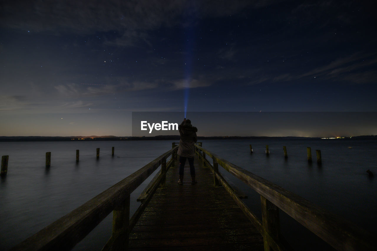 Pier over sea against sky at night