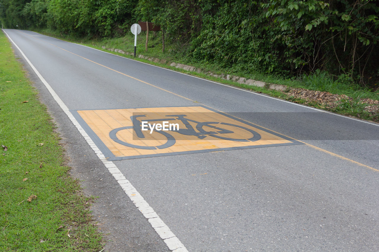 lane, road, sign, road surface, asphalt, transportation, symbol, road marking, marking, communication, infrastructure, tarmac, bicycle, plant, day, highway, zebra crossing, pedestrian crossing, guidance, road sign, the way forward, no people, bicycle lane, sidewalk, tree, nature, grass, outdoors, city, street, green, high angle view, arrow symbol, warning sign