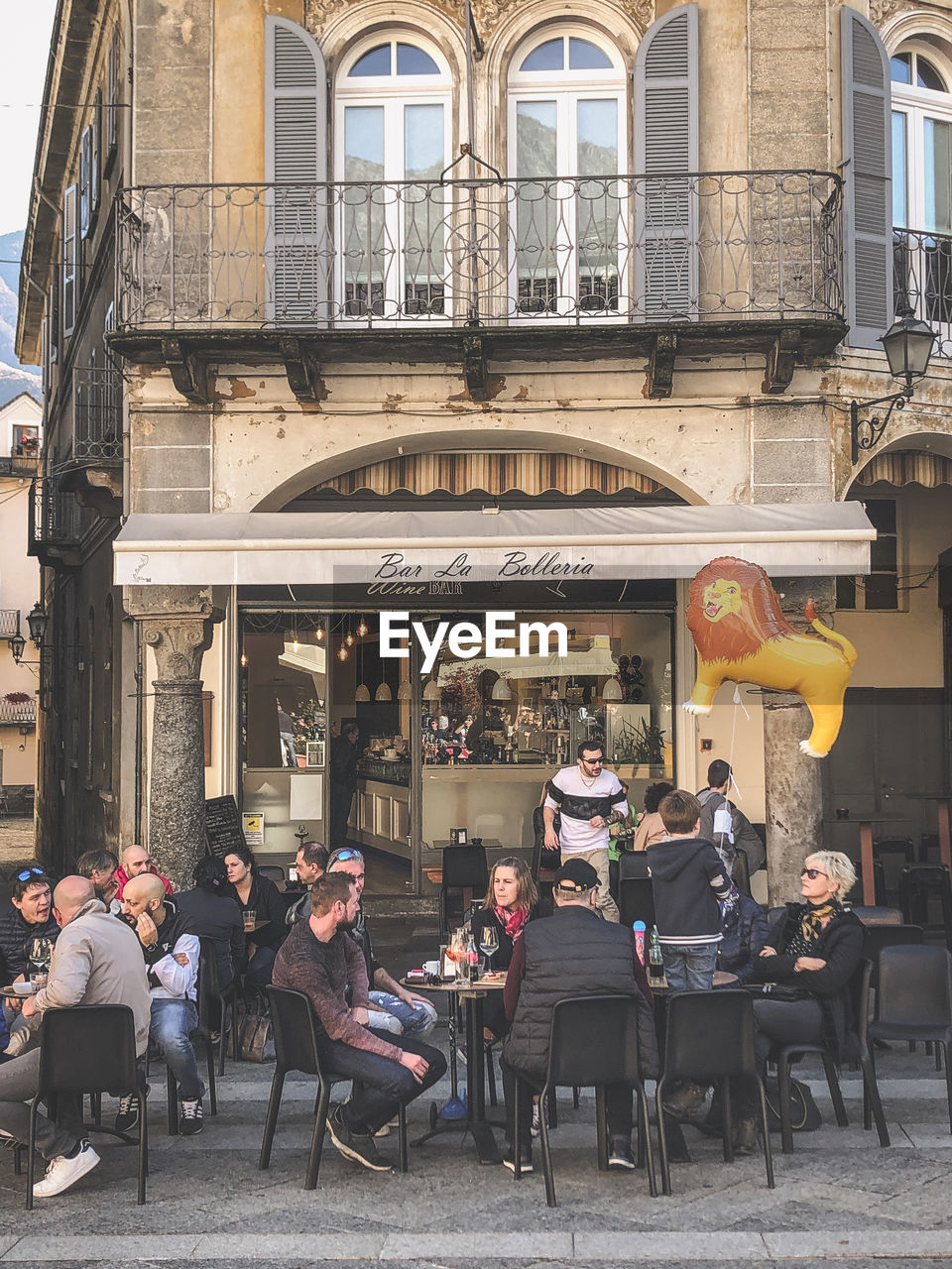 PEOPLE SITTING OUTSIDE RESTAURANT AGAINST BUILDINGS