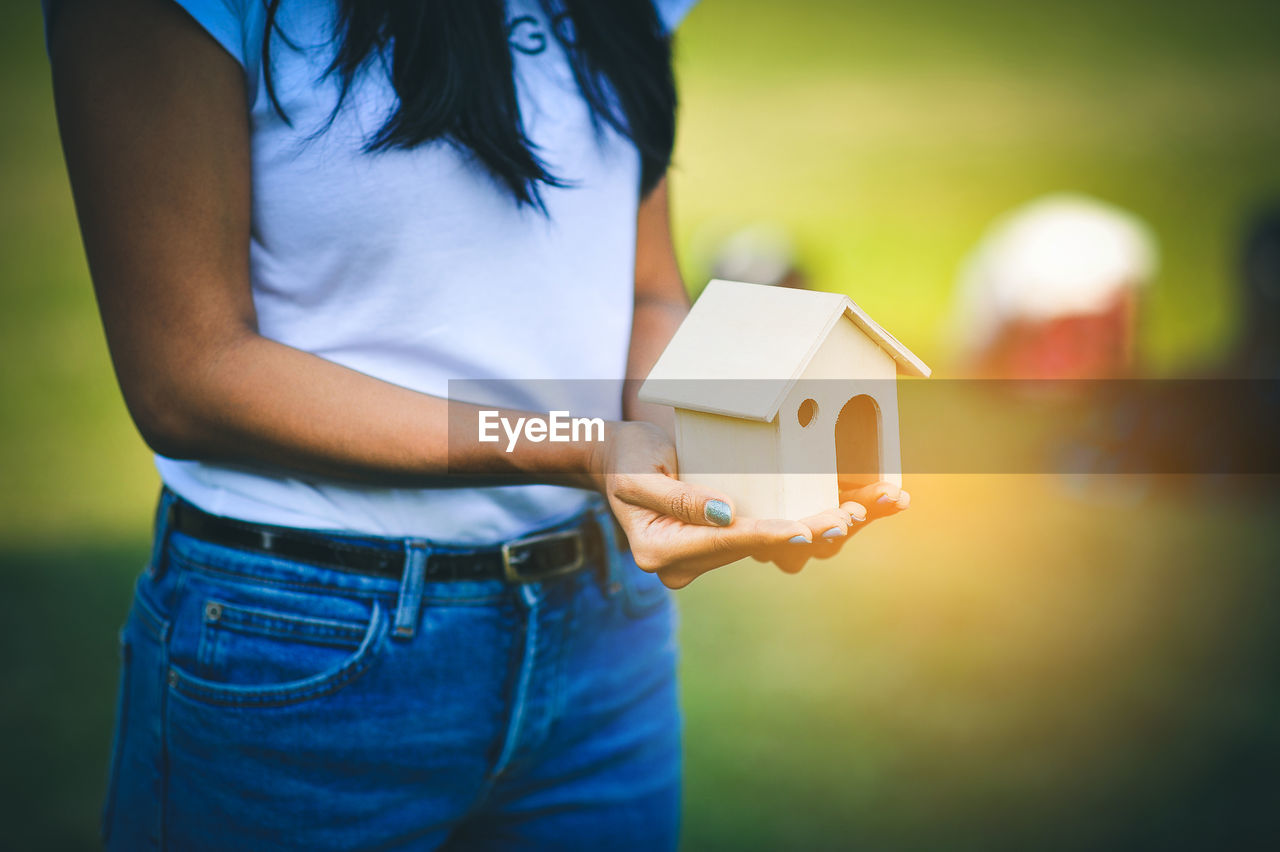 Midsection of woman holding model house