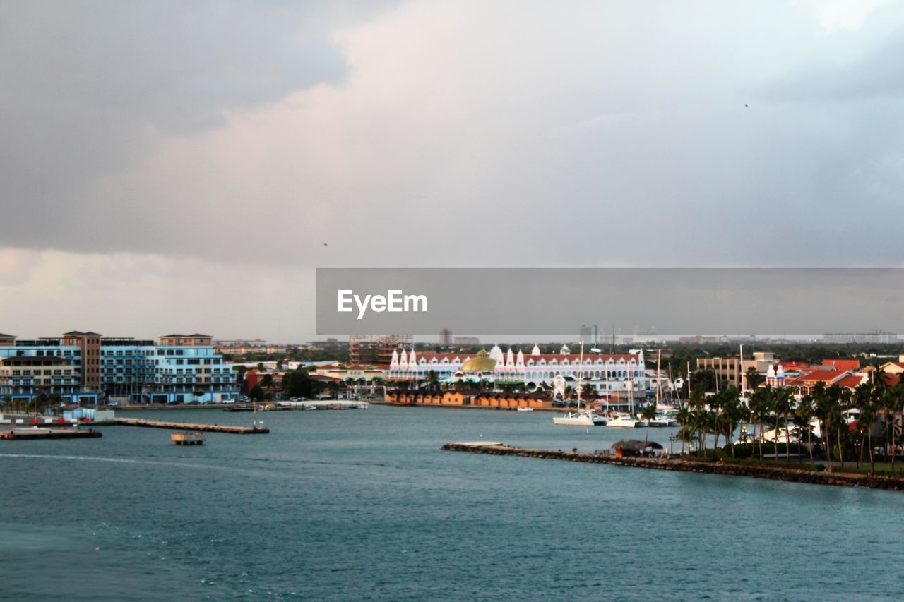 Sea and buildings in city against sky