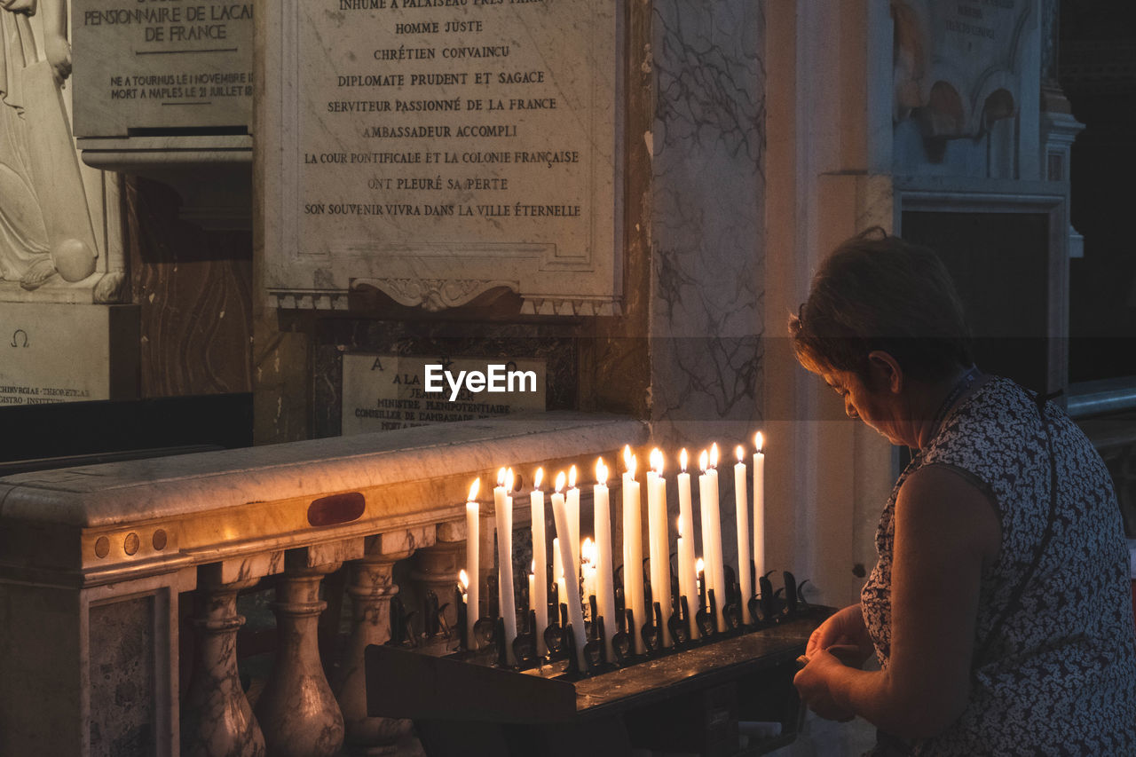 MIDSECTION OF WOMAN WITH ILLUMINATED CANDLES