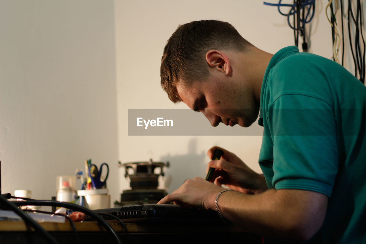 Young man, engineer soldering black laptop. electronic renovation in repair service. worker check