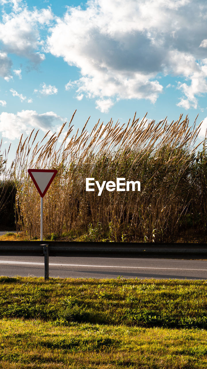 ROAD SIGN BY PLANTS ON FIELD