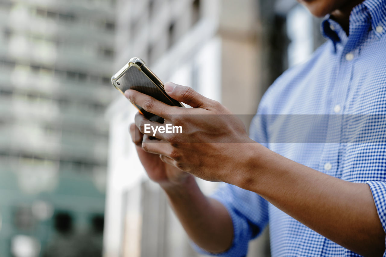 MIDSECTION OF MAN HOLDING SMART PHONE